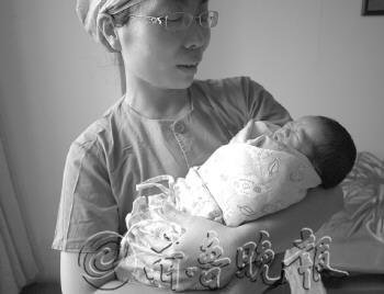 护士怀中的女婴多多。本报记者张榕博摄
